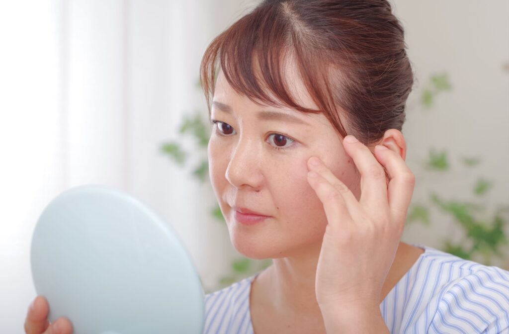 A person looking at their eye using a handheld mirror